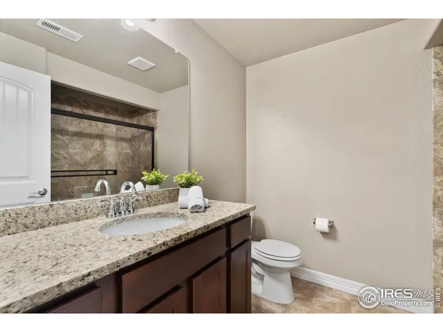 a bathroom with a granite countertop sink a toilet and a large mirror