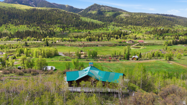6 Beaver Springs Rancheros Oakley, UT 84055 - Photo 55 of 68 Wood-sided structure featuring a vibrant green metal roof, set against a backdrop of rolling hills and dense woodlands
