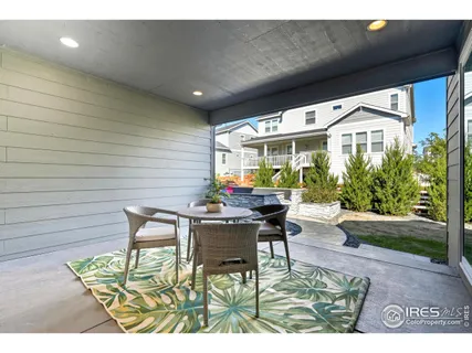 a patio with table and chairs and potted plants
