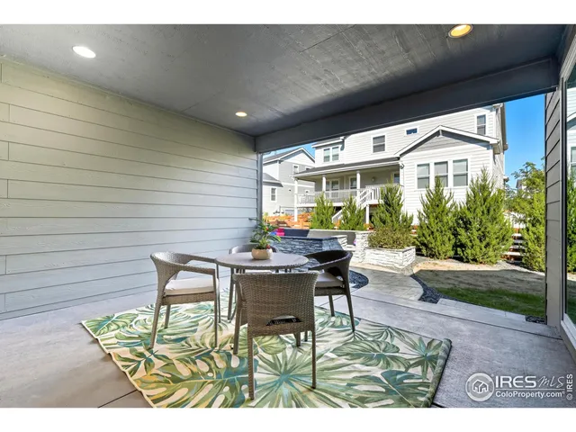 a patio with table and chairs and potted plants