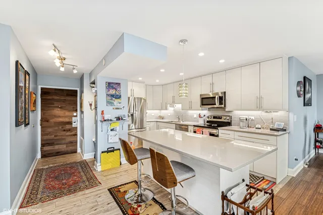 a kitchen with stainless steel appliances kitchen island granite countertop a refrigerator oven a sink a stove and white cabinets