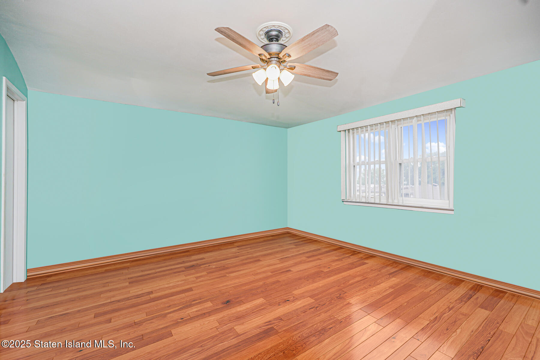 33 Ebey Lane Staten Island, NY 10312 - Photo 14 of 23 an empty room with wooden floor chandelier fan and windows