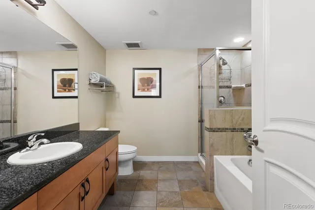 a bathroom with a granite countertop sink toilet and shower