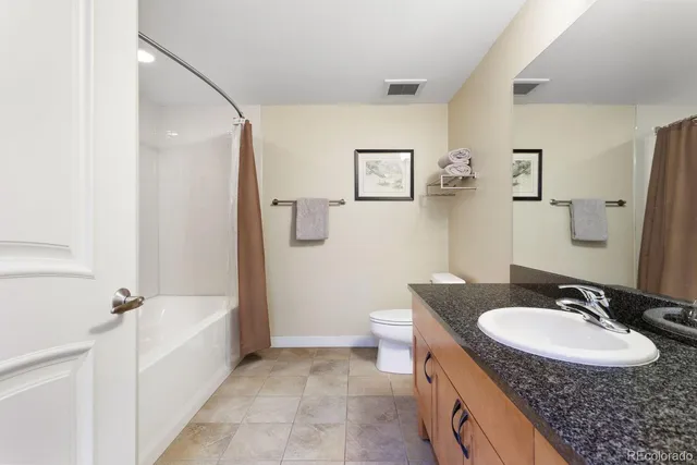 a bathroom with a granite countertop sink a mirror a toilet and bathtub