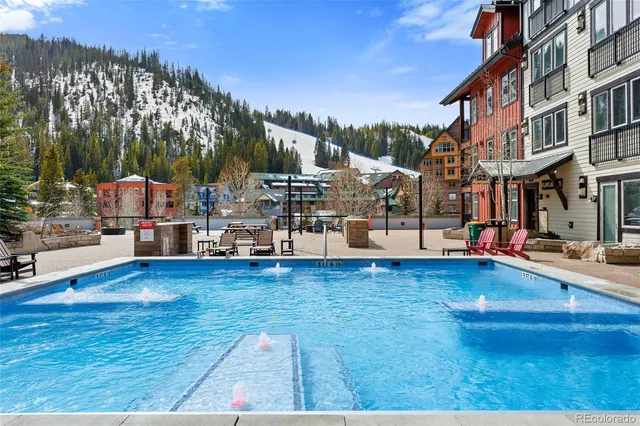 a view of pool of water with lawn chairs and mountain view