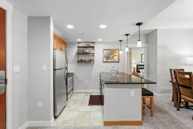 a living room with stainless steel appliances kitchen island granite countertop furniture and a refrigerator