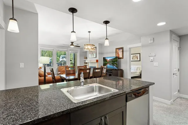 a kitchen with granite countertop a sink a counter top space and living room view