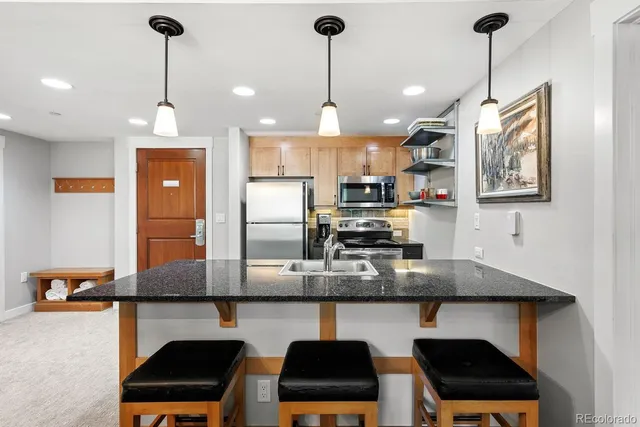 a kitchen with stainless steel appliances granite countertop a sink a stove and a refrigerator