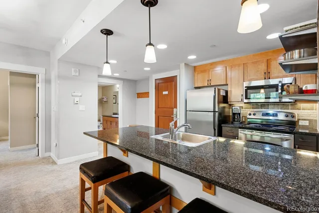 a kitchen with stainless steel appliances granite countertop a sink a stove and a refrigerator