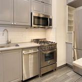 a kitchen with stainless steel appliances white cabinets and a stove top oven