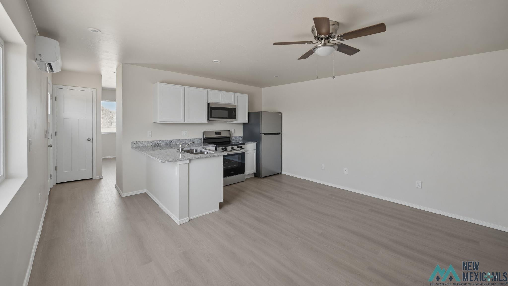 106 Inca Street Elephant Butte, NM 87935 - Photo 25 of 36 Kitchen with stainless steel appliances, white cabinets, ceiling fan, a peninsula, and light wood finished floors
