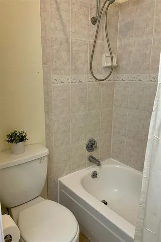 a white toilet sitting next to a bath tub and a shower