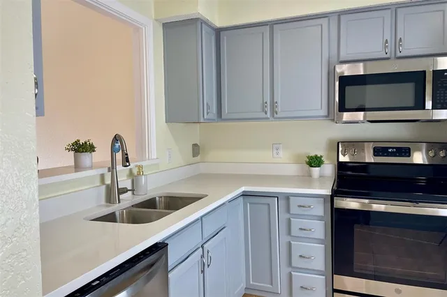 a kitchen with stainless steel appliances granite countertop a sink dishwasher a stove and a microwave oven with cabinets