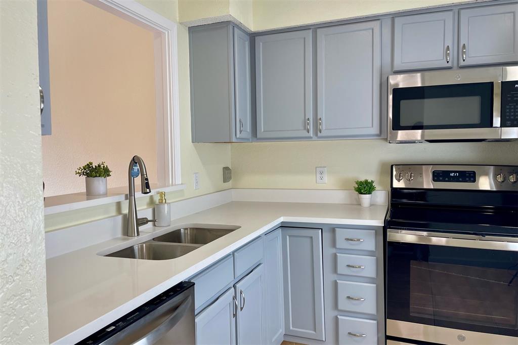4748 Old Bent Tree Lane, Unit 1404 Dallas, TX 75287 - Photo 2 of 25 a kitchen with stainless steel appliances granite countertop a sink dishwasher a stove and a microwave oven with cabinets