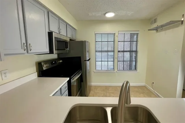 a kitchen with stainless steel appliances a stove a sink a microwave a refrigerator and cabinets