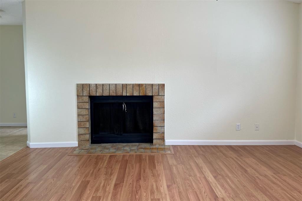 4748 Old Bent Tree Lane, Unit 1404 Dallas, TX 75287 - Photo 8 of 25 a view of an empty room with wooden floor and a fireplace