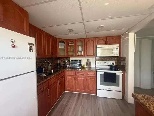 a kitchen with stainless steel appliances granite countertop a stove a sink dishwasher a refrigerator and a microwave oven with wooden floor