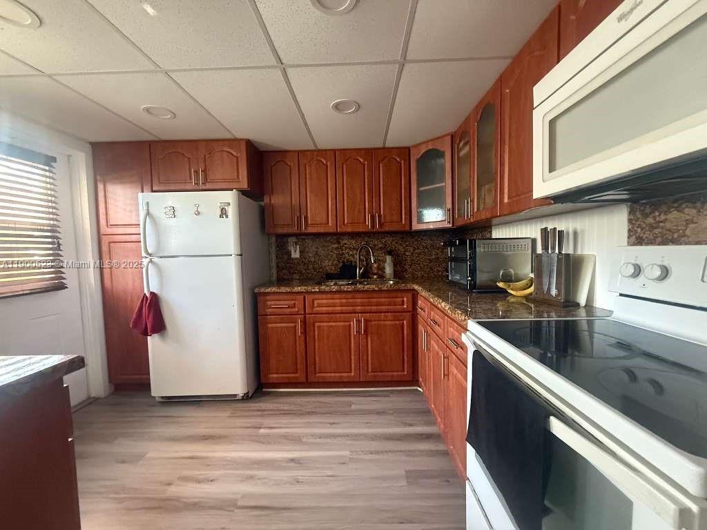 18900 Northeast 3rd Court, Unit 509 Miami, FL 33179 - Photo 6 of 19 a kitchen with a refrigerator a stove a sink dishwasher and wooden cabinets with wooden floor
