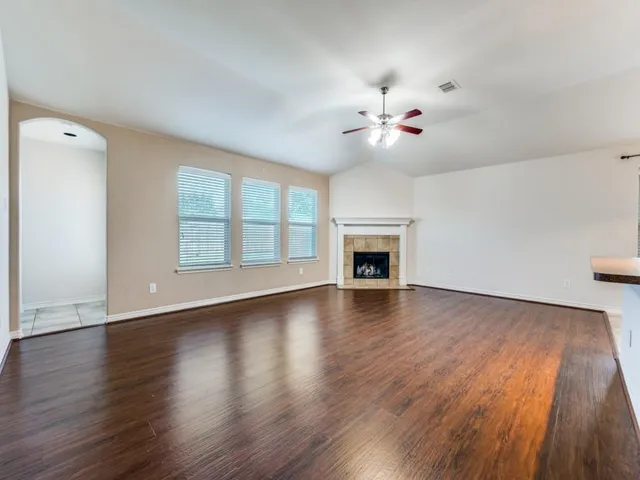 a view of an empty room with a fireplace and wooden floor