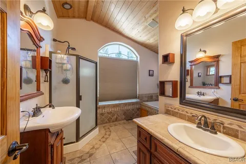 a bathroom with a sink double vanity granite tub shower and a mirror