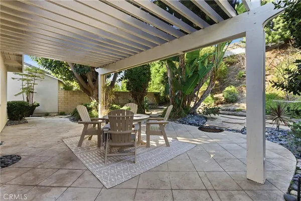 a view of a patio with table and chairs potted plants and large tree