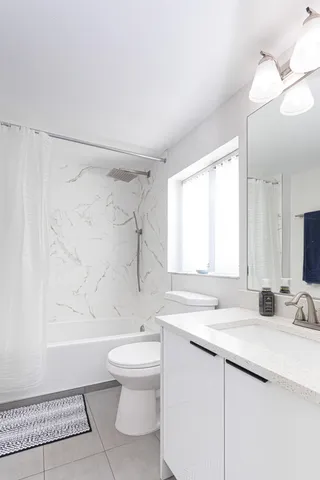 a bathroom with a granite countertop sink a toilet and shower