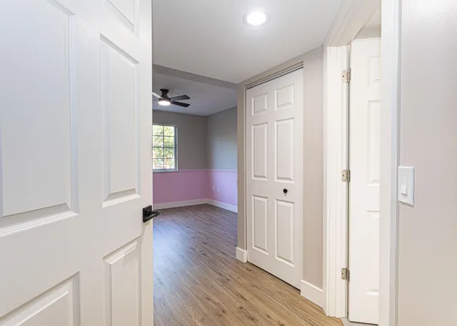 a view of an empty room with wooden floor and a window