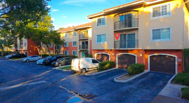 a front view of a building with lots of trees and plants