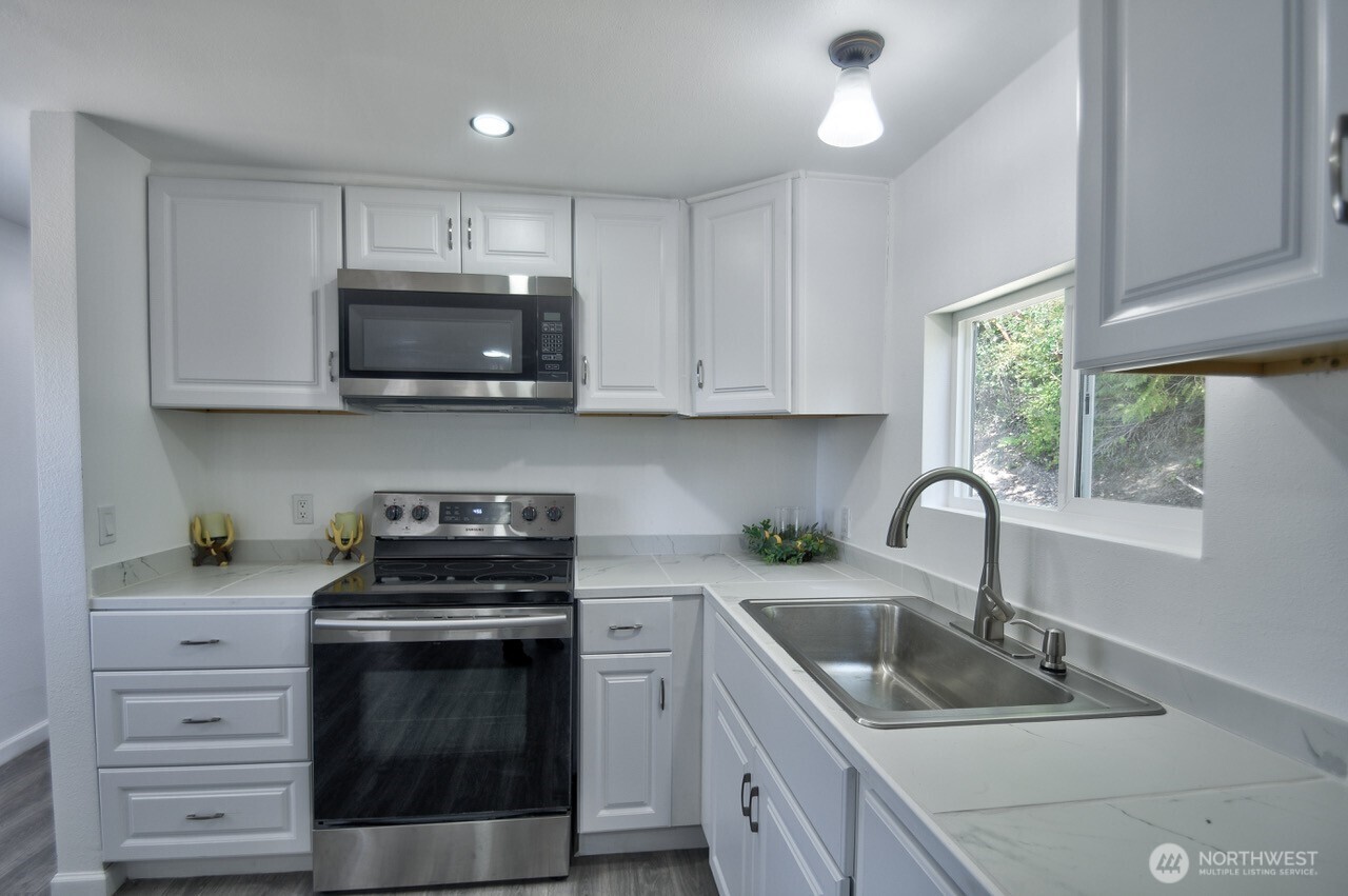 15503 Cedar Park Road Southeast, Unit 35C Olalla, WA 98359 - Photo 3 of 13 a kitchen with sink a microwave and cabinets