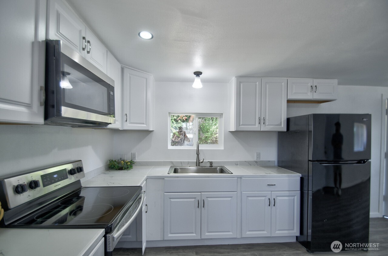 15503 Cedar Park Road Southeast, Unit 35C Olalla, WA 98359 - Photo 4 of 13 a kitchen with kitchen island granite countertop a sink cabinets and stainless steel appliances