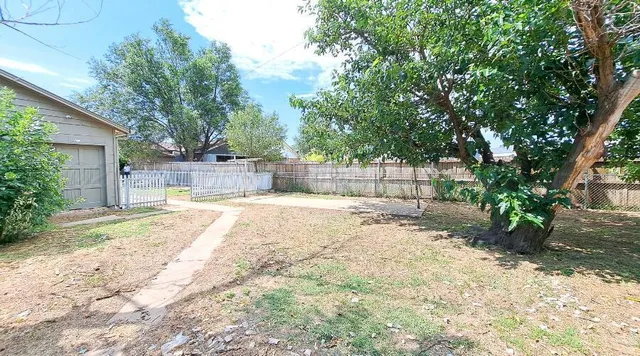 a view of a yard with large tree and wooden fence