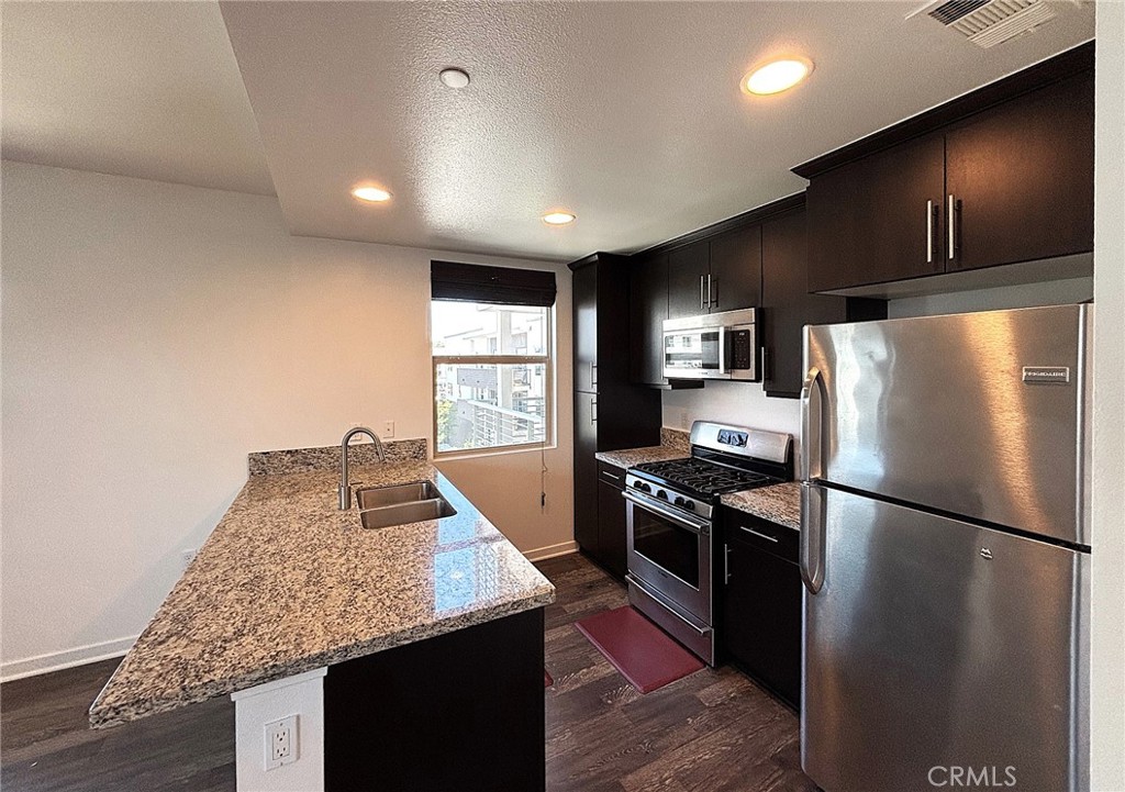 612 East Carson Street, Unit 303 Carson, CA 90745 - Photo 13 of 51 a kitchen with stainless steel appliances granite countertop a refrigerator a stove and a sink