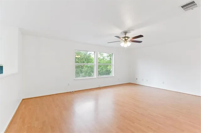 an empty room with wooden floor closet and fan