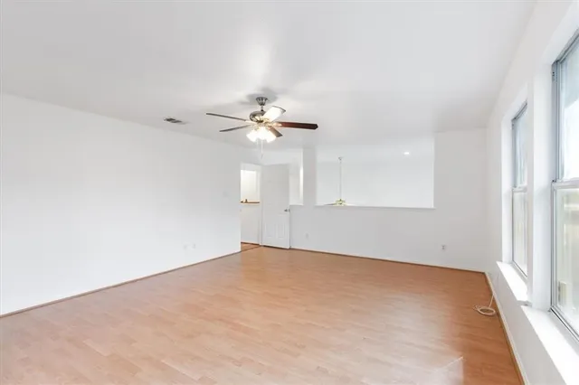 an empty room with a window and a ceiling fan