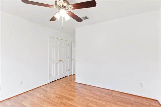 an empty room with wooden floor closet and windows