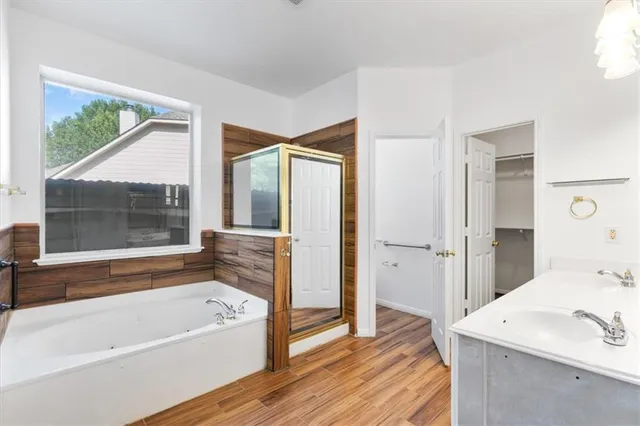 an empty room with wooden floor ceiling fan and windows