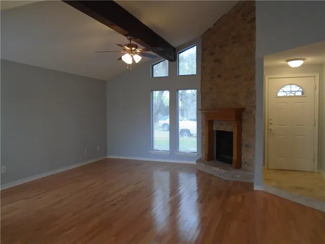 a view of an empty room with wooden floor and a fireplace