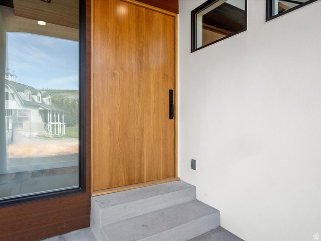 2610 Foxridge Road Garden City, UT 84028 - Photo 16 of 71 Wood-finish entryway pivot door with a black handle, flanked by a full-height window and transom windows