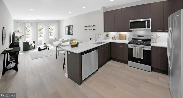 a kitchen with stainless steel appliances a stove a sink a microwave a refrigerator and cabinets