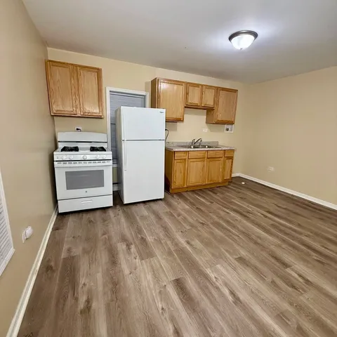 a kitchen with a refrigerator a stove top oven a sink and dishwasher with wooden floor