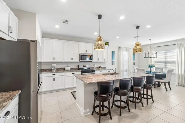 a kitchen with stainless steel appliances granite countertop a stove refrigerator a sink dishwasher a dining table and chairs with wooden floor
