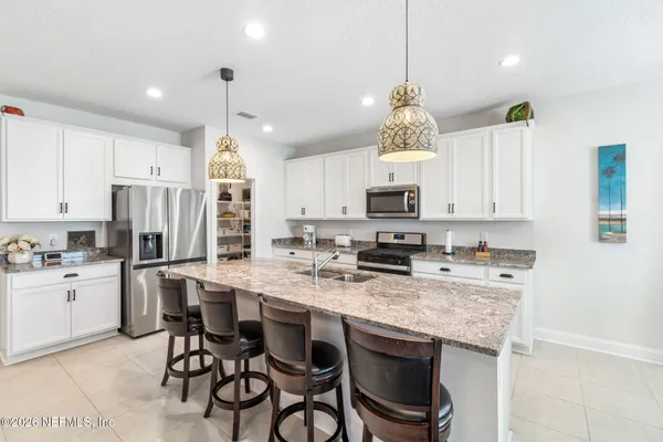 a kitchen with stainless steel appliances granite countertop a sink stove refrigerator and cabinets