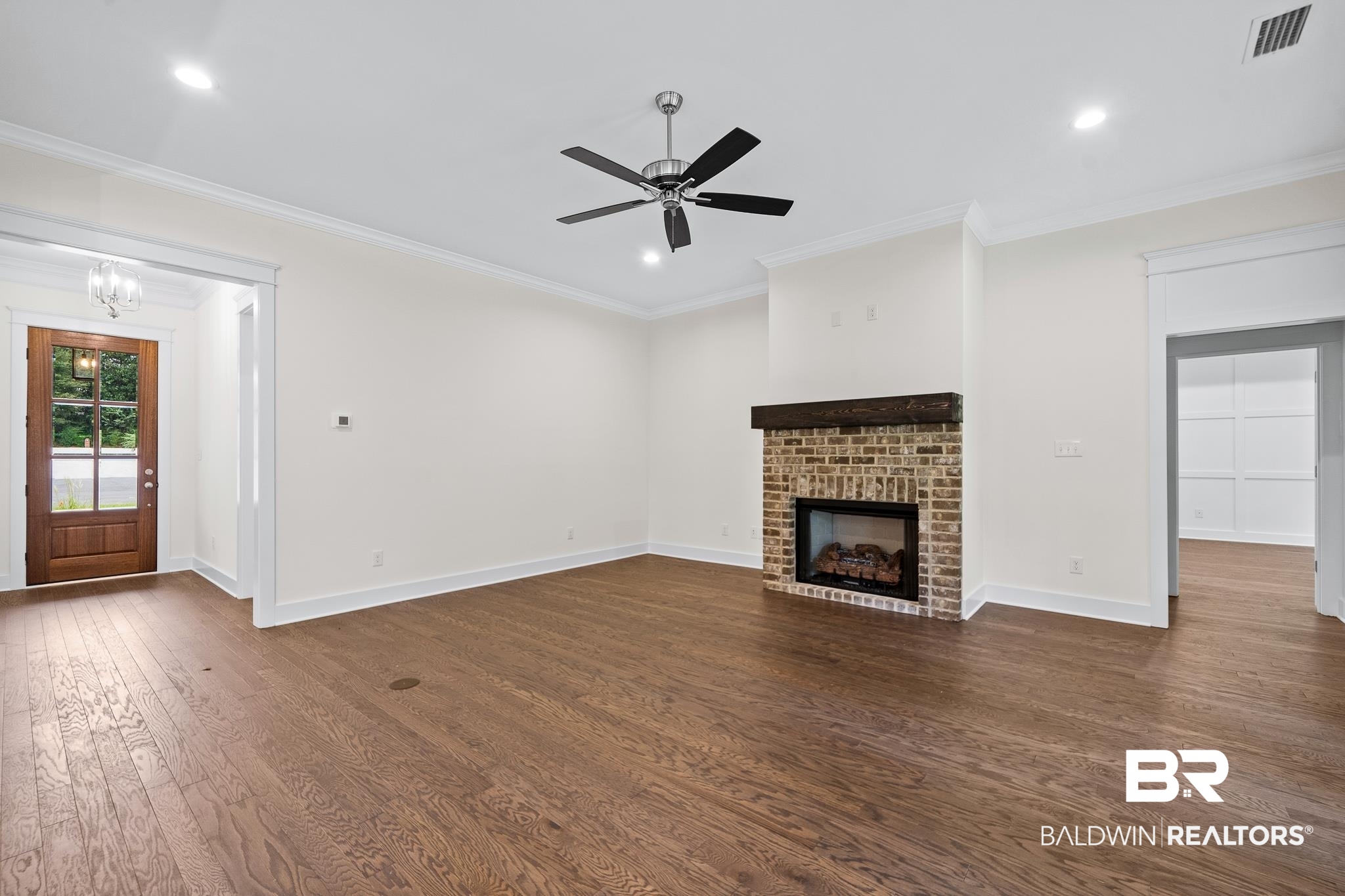 29 Signal Hill Road Daphne, AL 36527 - Photo 7 of 36 Unfurnished living room featuring a fireplace, dark hardwood / wood-style flooring, ornamental molding, and ceiling fan with notable chandelier