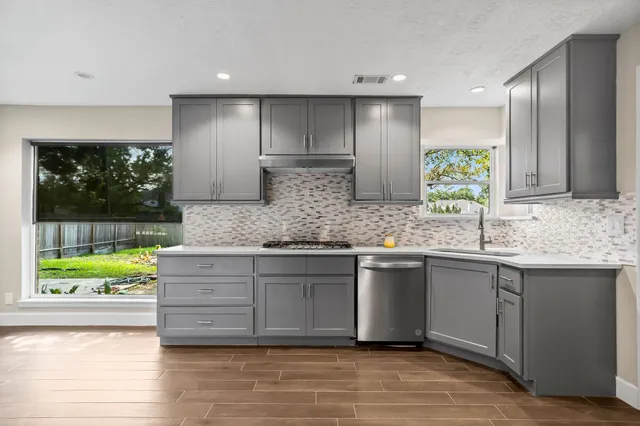 a kitchen with stainless steel appliances granite countertop a sink and a large window