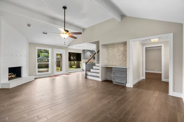 a view of an empty room with wooden floor fireplace and a window