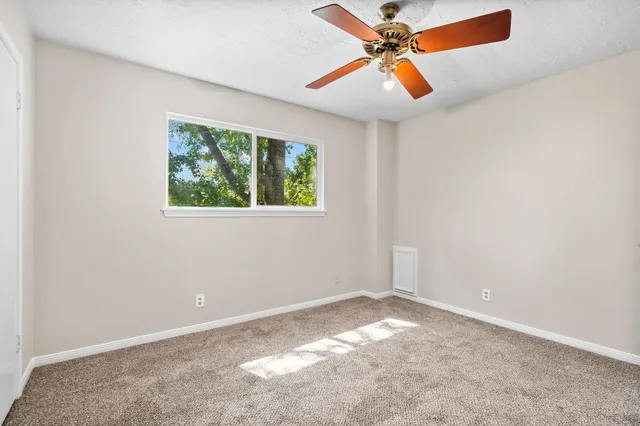 an empty room with a window and a fan