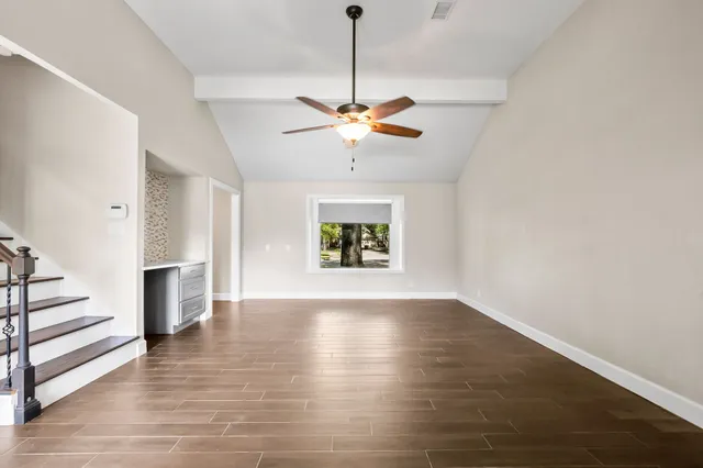 a view of an empty room with a window and wooden floor