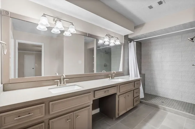 a bathroom with a double vanity sink mirror and chandelier