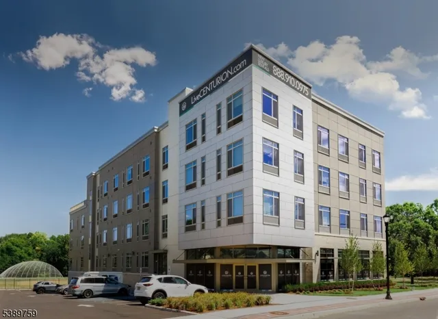 a front view of a building with lot of cars and trees