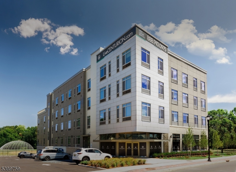a front view of a building with lot of cars and trees